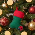 A felt Christmas stocking with a green body, red cuff and hanging ribbon, and a ladybug applique on the foot.
